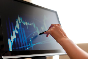 Financial Data Concept:Woman hand touch the computer screen with pen.Financial and business graphs,...