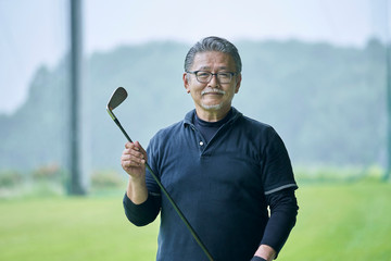 ゴルフ場で練習をするシニアの男性