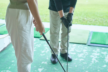 ゴルフ場でゴルフを教える男性と教わる女性