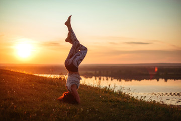 Yoga practice and meditation in nature in sunrise. Woman practicing near big river Kama.