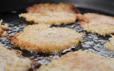 Detailaufnahme von knusprigen Kartoffelpuffer bratend in einer Pfanne mit viel Öl