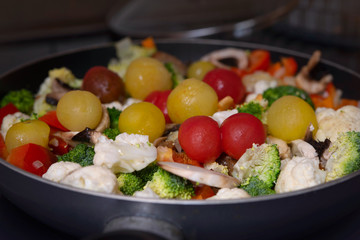 Ragout of vegetables with cauliflower, broccoli, paprika, cherry tomatoes in pan.