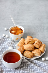 Tasty breakfast. Homemade sweet cinnamon cookies and cup of tea. Apple confiture on background