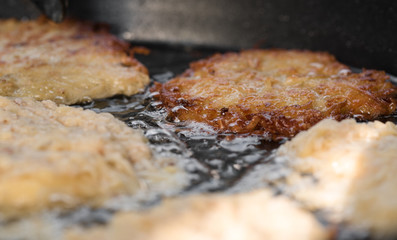 Detailaufnahme von knusprigen Kartoffelpuffer bratend in einer Pfanne mit viel Öl