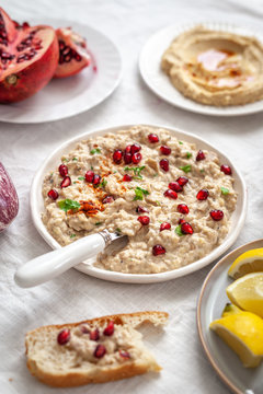 Mezze table with vegan baba ganoush with pomegranate seeds and hummus on white table cloth