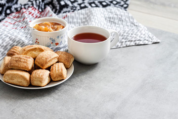 Tasty breakfast. Homemade sweet cinnamon cookies and cup of tea. Apple confiture on background
