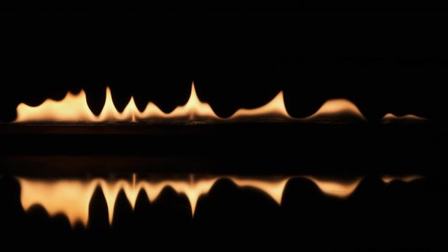 Slow motion, pulsating fire and its reflection on a black background. Texture of fire on a black background. Fire flames.