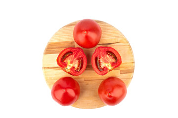 Top view. Ripe tomatoes and tomato halves on a wooden cutting board.