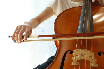 チェロを弾く若い女性　柔らかい光が射す部屋で woman playing the  cello