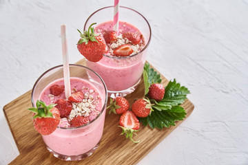 Strawberry milk shake in glass with straw and fresh berries on a white background
