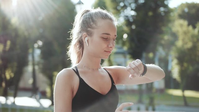 Close up fitness woman look at smart watch and running at sunlight outdoors athlete workout equipment app technology active device slow motion