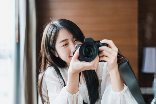 Asian woman taking photo by mirrorless digital camera, with smiling face