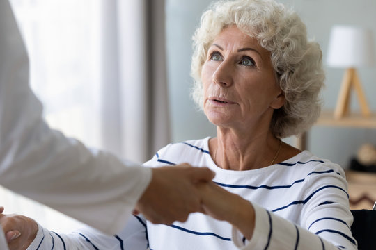 Head Shot Hopeful Middle Aged Handicapped Hoary Woman Holding Hands Of Professional Physiotherapist, Starting Rehabilitation Procedures Indoors, Trying Walking With Help, Medical Service Concept.