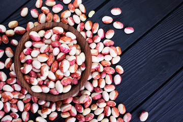 Fresh beans on a dark wooden table. Beans with red spots. Food background