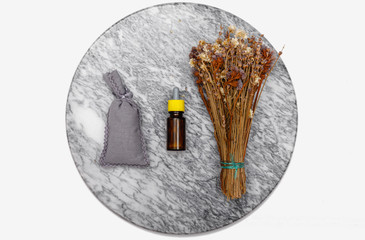 Essential oil and lavender flowers. Selection of essential oil on marble tabel with various organic herbs and flowers in the background.
