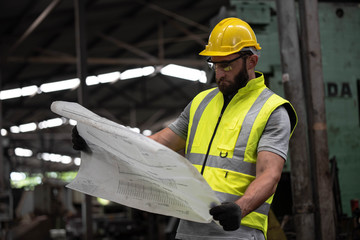 Portrait of technician man or industrial worker with hardhat or helmet, eye protection glasses and vest working electronic machinery on laptop and mechanical  in Factory of manufacturing place