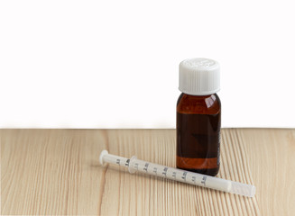 A bottle of medicine syrup with a syringe for kids on the white background with the copy space.