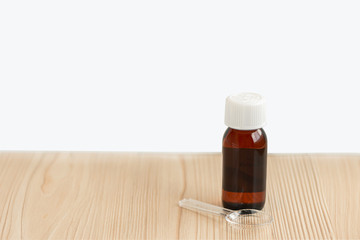 A bottle medicine syrup with a spoon on the white background with the copy space.