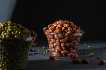 Pinto beans in glass pot with blurry mung bean image black background