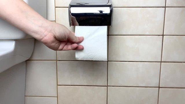 woman in wc room tears off white multilayer toilet paper, concept of cleanliness and hygienic routine