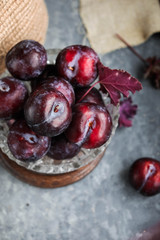 Red plums on a vintage plate on a gray background. Pieces of fruit. View from above.