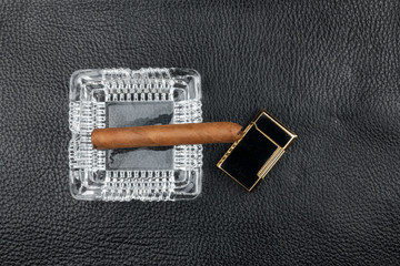 Ashtray, cigar and lighter lie on black natural leather. - 371787908