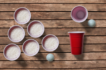 Beer pong scene with ping pong ball and cups on a wooden table 