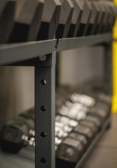 Sports background. Interior gym with sports equipment. Fitness background with close up selective focus to a rack with plenty of blurred copyspace.