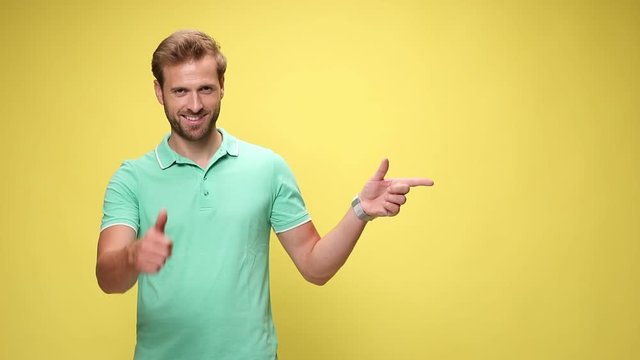casual man smiling, pointing fingers to side and making thumbs up gesture on yellow background