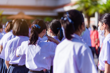 The back view of Asian high school students in white uniforms on the semester start wearing masks during the Coronavirus 2019 (Covid-19) epidemic.