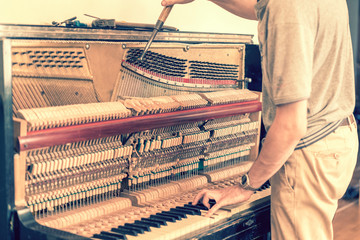 Piano tuning process. closeup of hand and tools of tuner working on grand piano. Detailed view of...
