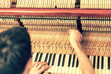 Piano tuning process. closeup of hand and tools of tuner working on grand piano. Detailed view of...