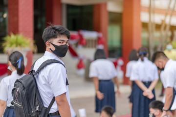 Obraz na płótnie Canvas Asian male high school student in white uniform on the semester start wearing masks during the Coronavirus 2019 (Covid-19) epidemic.