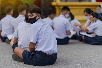 Asian male high school student in white uniform on the semester start wearing masks during the Coronavirus 2019 (Covid-19) epidemic.