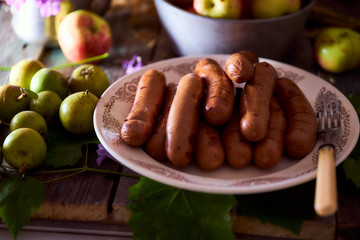 grilled sausages are on a white plate with small pears
