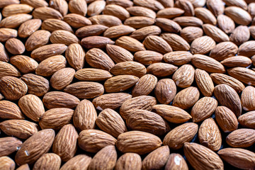 background of raw shelled almonds fully filled side view at an angle close up with a selective shallow depth of field