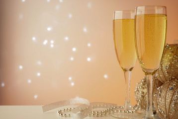 sparkling champagne in glass glasses close-up on a light background with flickering lights in bokeh with New Year's toys and tinsel