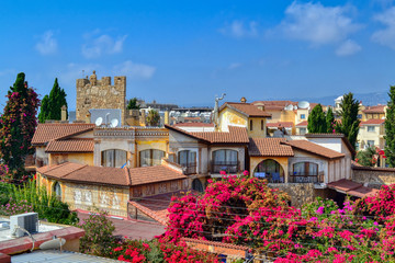 Fototapeta na wymiar Tourist apartments surrounded by flowering bushes in Paphos, Cyprus. View of the city from the roof of the building, the hotel is stylized as antique buildings. The streets of the tourist area.