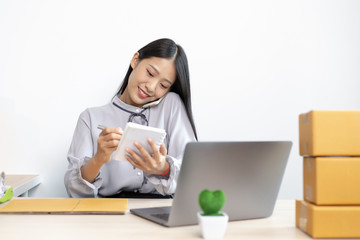 Young Asian woman is selling products online and is confirming an order from a customer.