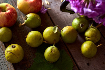 Composition of village red apples and small pears on a wooden table