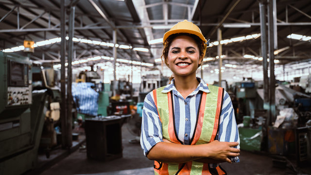 attractive young african woman smiling and working engineering in industry.Portrait of young female worker in the factory.Work at the Heavy Industry Manufacturing Facility concept.