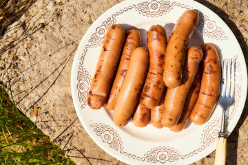 grilled sausages are on a white plate. Top view.