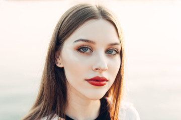 Beautiful 20 year old girl in the rays of the sun outdoors. A charming calm young woman