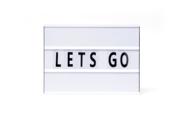 Lets go. Text on a vintage lightbox display placed on a white table on a light background. 