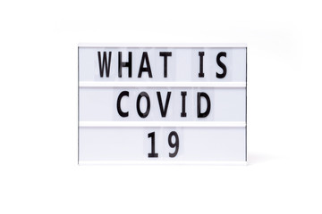 What is covid 19. Text on a vintage lightbox display placed on a white table on a light background. 