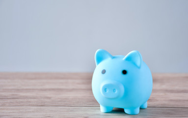 A blue piggy bank and a coin on a wooden table to save money .