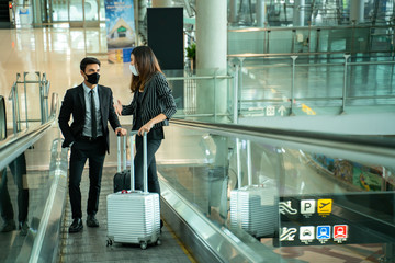New normal and social distance concept.Businessman and businesswoman having conversations while wearing face mask on escalator.Couple in medical masks on escalator in Airport. Coronavirus pandemic.