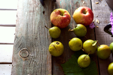 Composition of village red apples and small pears on a wooden table