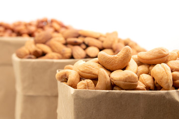 Close up of roasted cashew nut in paper bag on white background