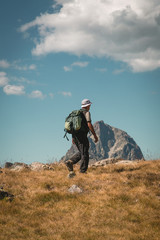 Fototapeta na wymiar Man with backpack hike to the top of the mountain and dramatic scenery summer landscape wellness selective focus rear view, freedom concept.